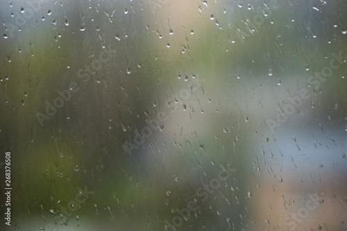 Rain drops running down dirty glass window pane. Summer time