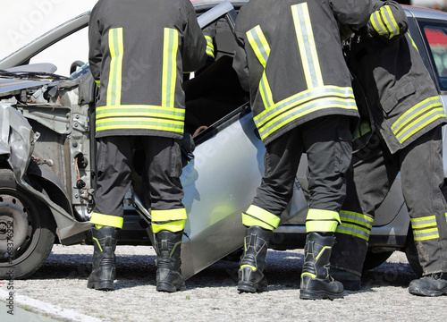 firemen remove the door of a car after a car accident to recover