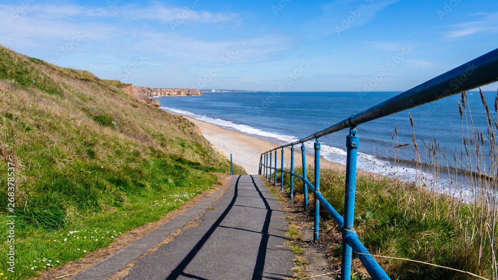 Stairway down to Seaham Hall Beach in County Durham, England UK.  Image taken on a warm sunny day showing blue sea, golden sand and blue sky.