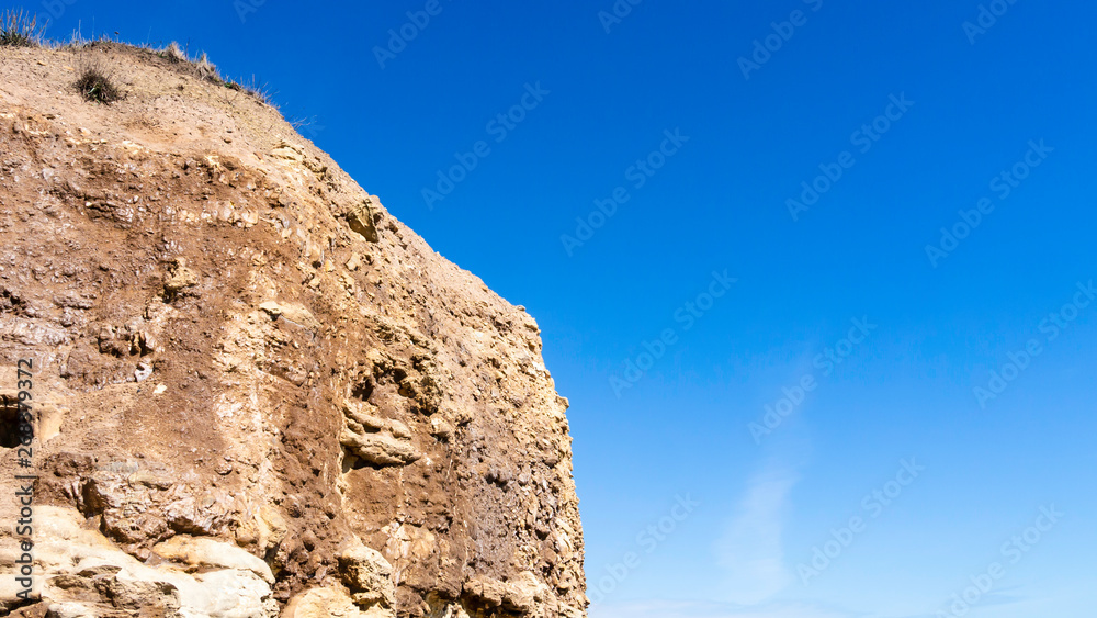 Desert like cliff face made up of rocks, sandstone and dirt at Seaham Hall Beach in County Durham England, basking in the sunshine of a warm and very sunny day.