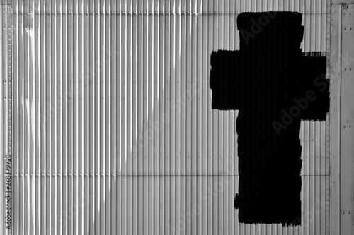 фотографія A black cross painted on a white metal door
