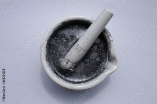 Fine particles of aluminum on the surface of the water in a ceramic mortar with pestle. photo