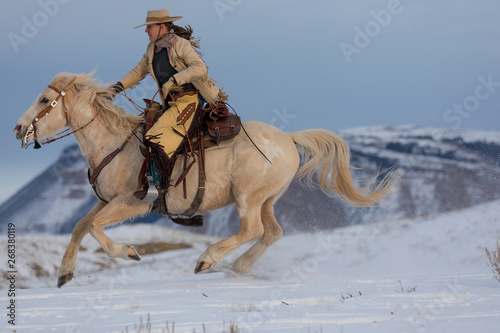 Side view of cowgirl riding horse during winter