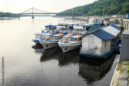 Tourist Ships moored on the Dnieper River embankment in Kyiv. Pedestrian bridge on the background. Kyiv, Ukraine. 16-06-2019