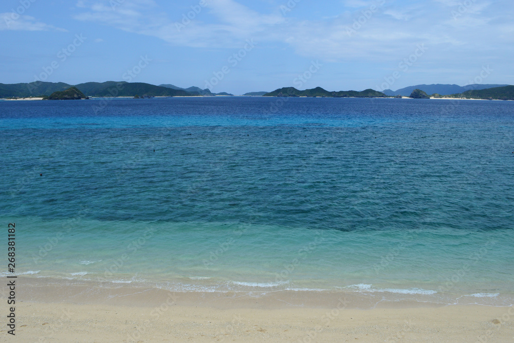 Obraz premium 背景に島のある白い砂浜とエメラルドグリーンの海