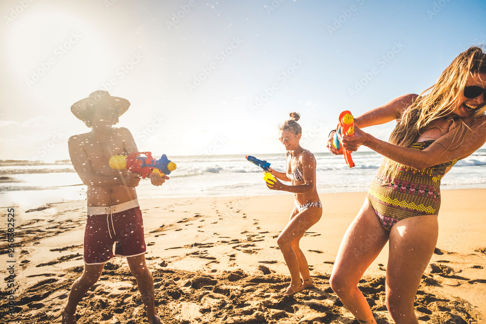 Group of happy young people enjoying the summer holiday vacation at the  beach playing with water guns together in friendship having fun - outdoor  funny play couples Stock Photo | Adobe Stock