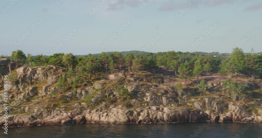 sailing along a rocky island at the scandinavian coast, with trees and sea. sailing along a rocky island at the scandinavian coast, with trees and sea.