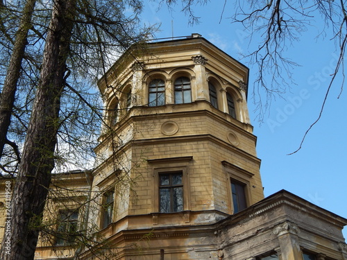 Beautiful yellow turret of an abandoned building against a blue sky surrounded by trees