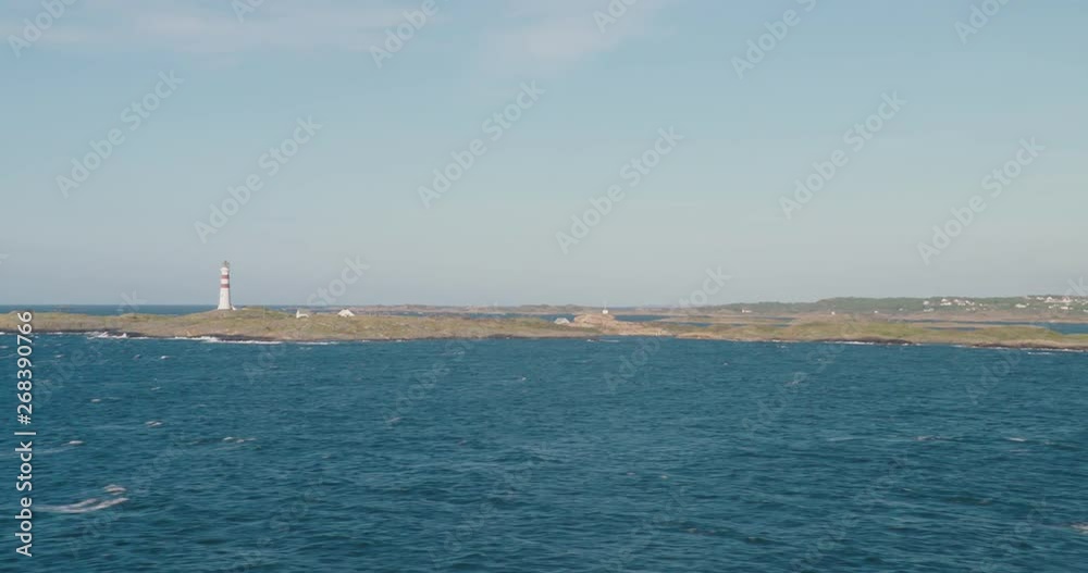 Lighthouse on a rocky island, choppy sea, blue sky Lighthouse on a rocky island, choppy sea, blue sky