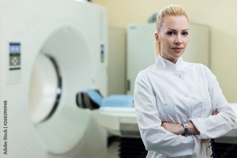 Portrait of confident female radiologist with CT scan machine in the background. Portrait of confident female radiologist with CT scan machine in the background.