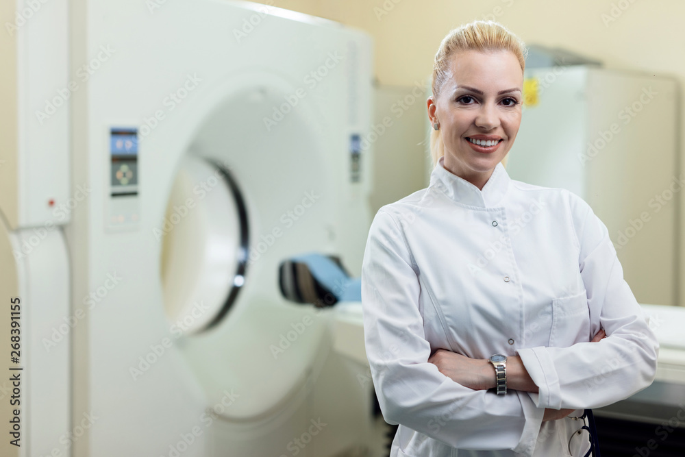 Confident female doctor standing in front of MRI scanner at clinic. Confident female doctor standing in front of MRI scanner at clinic.