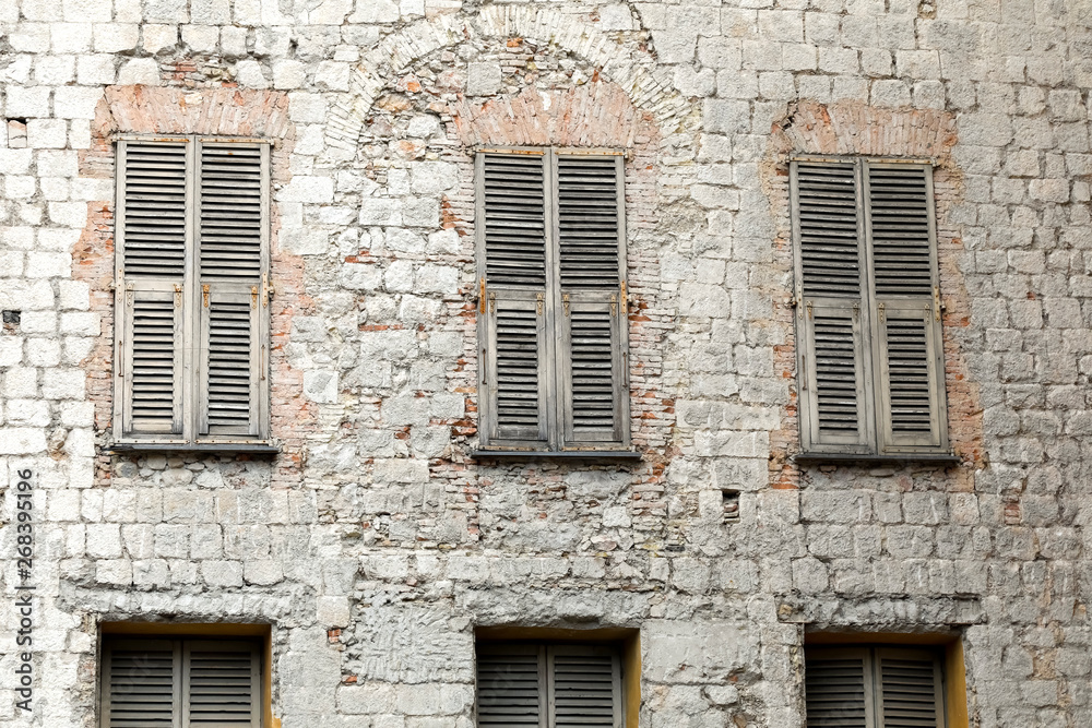 The stone facade with closed shutters on windows