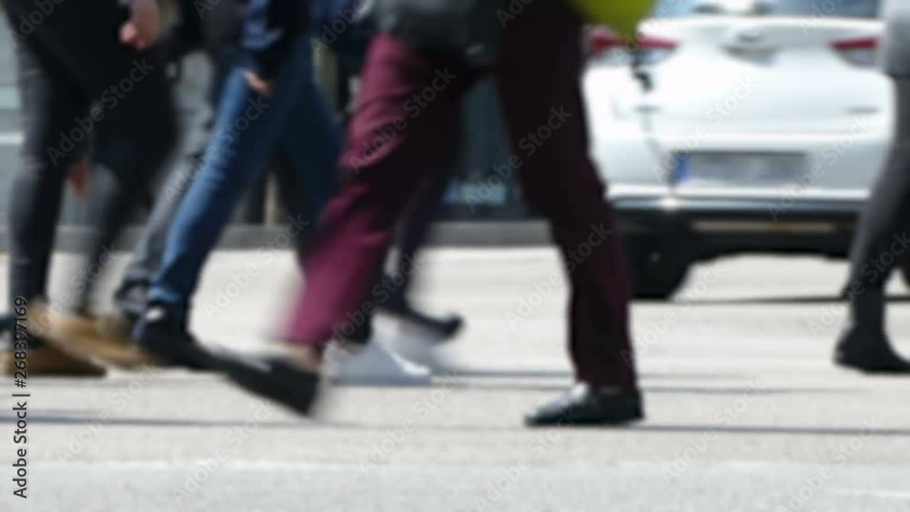Side view blurry pedestrians walking.Time Lapse. Detail of legs crossing a street in the city of Barcelona with traffic of background. Side view blurry pedestrians walking.Time Lapse. Detail of legs crossing a street in the city of Barcelona with traffic of background.