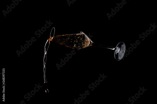 cocktail pouring out of a glass on a black background © Valery