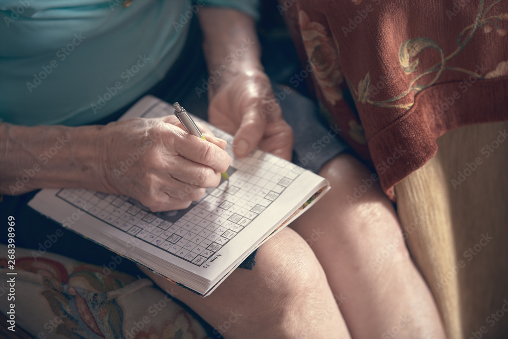 Obraz premium Photograph of an elderly woman doing crosswords at home. Huelva, Spain.