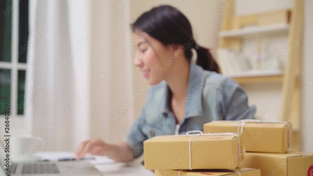 Smart Asian young entrepreneur business woman owner of SME online checking product on stock and save to laptop working at home. Small business owner at home office concept. Smart Asian young entrepreneur business woman owner of SME online checking product on stock and save to laptop working at home. Small business owner at home office concept.