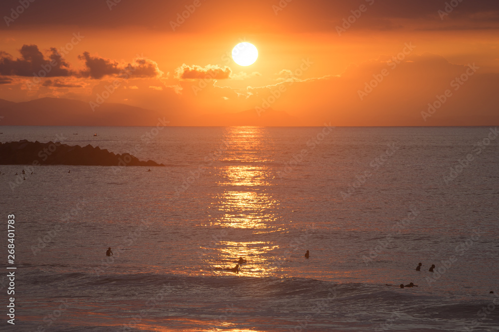 Surfer riding wave during sunset with scenic background landscape