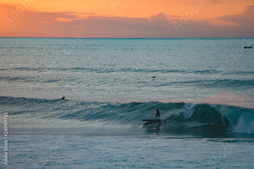 Surfer riding wave during sunset with scenic background landscape
