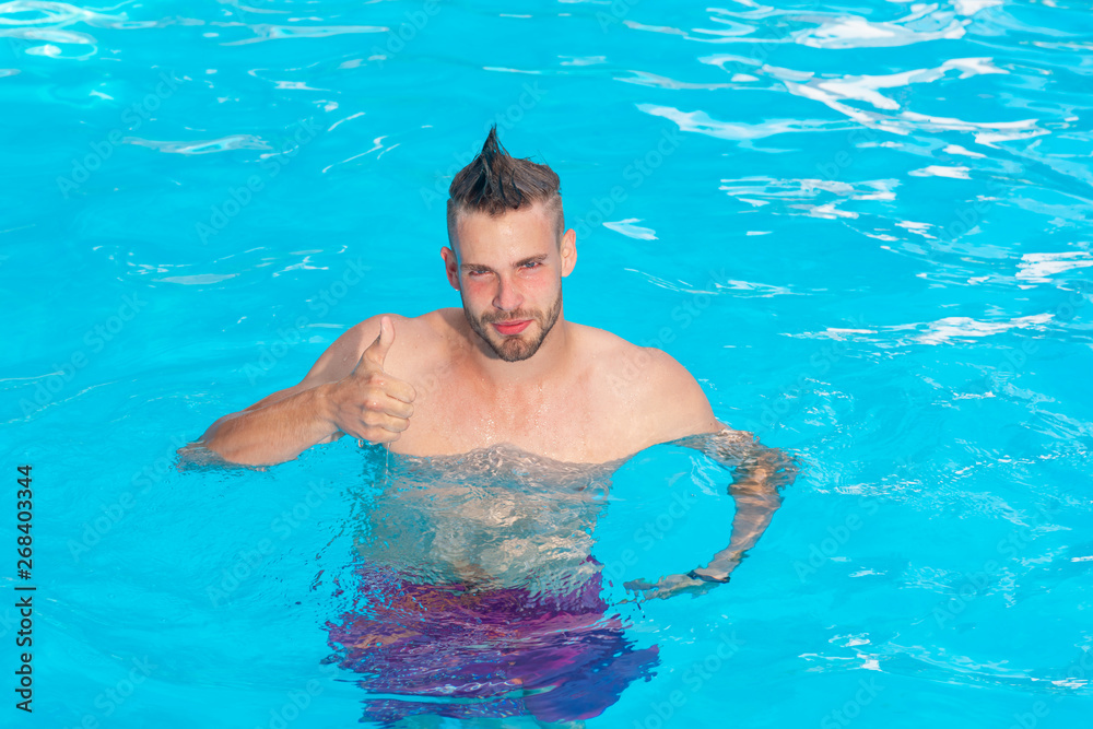 Handsome guy resting while swimming pool outdoor. Sexy man on Caribbean Sea in Bahamas. Ocean water background - excited. Young man active leisure - swimming pool concept.