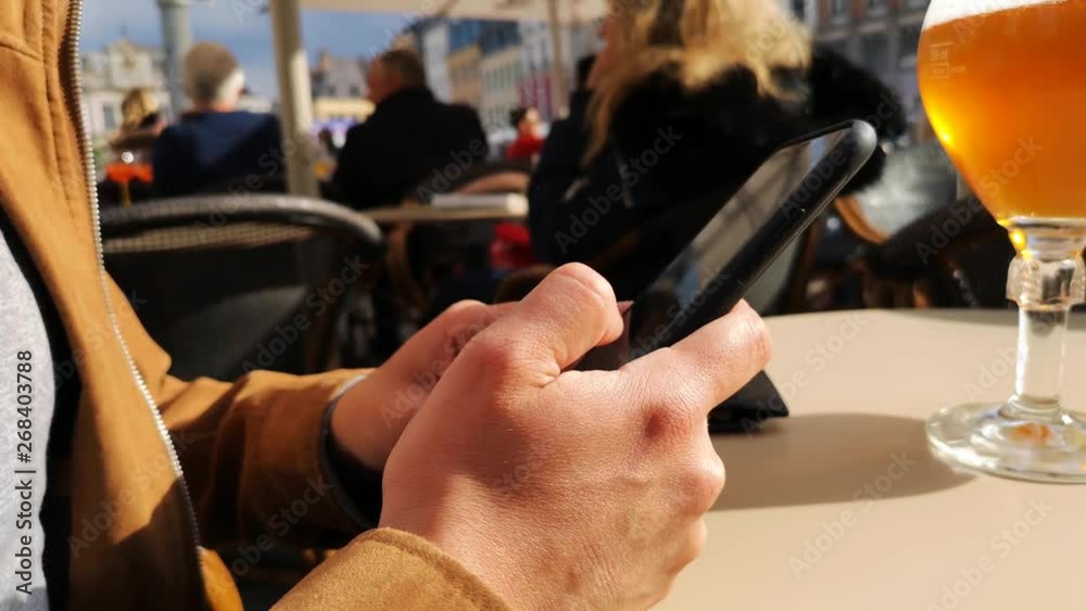 Zoom on the hands of a man using his smartphone on a café terrace Zoom on the hands of a man using his smartphone on a café terrace