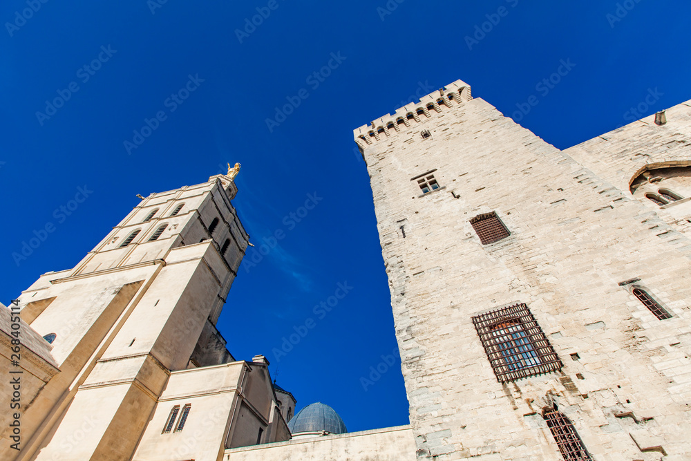 Avignon cathedral next to Papal palace under blue sky in Avignon, France