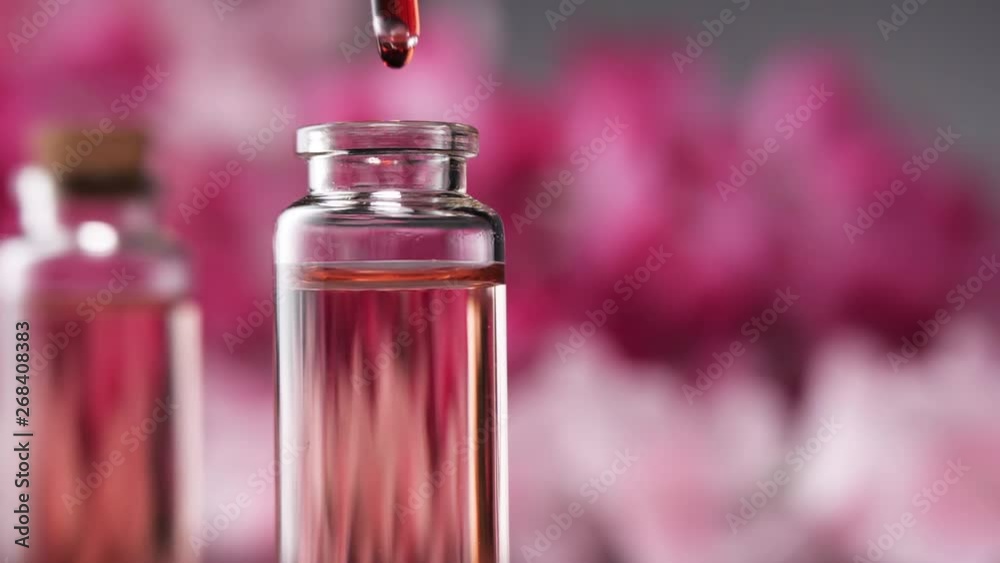 Blend of essential oils. Making some aroma liquids, perfume. Drops falling from pippet to little glass bottle. Slowmotion.