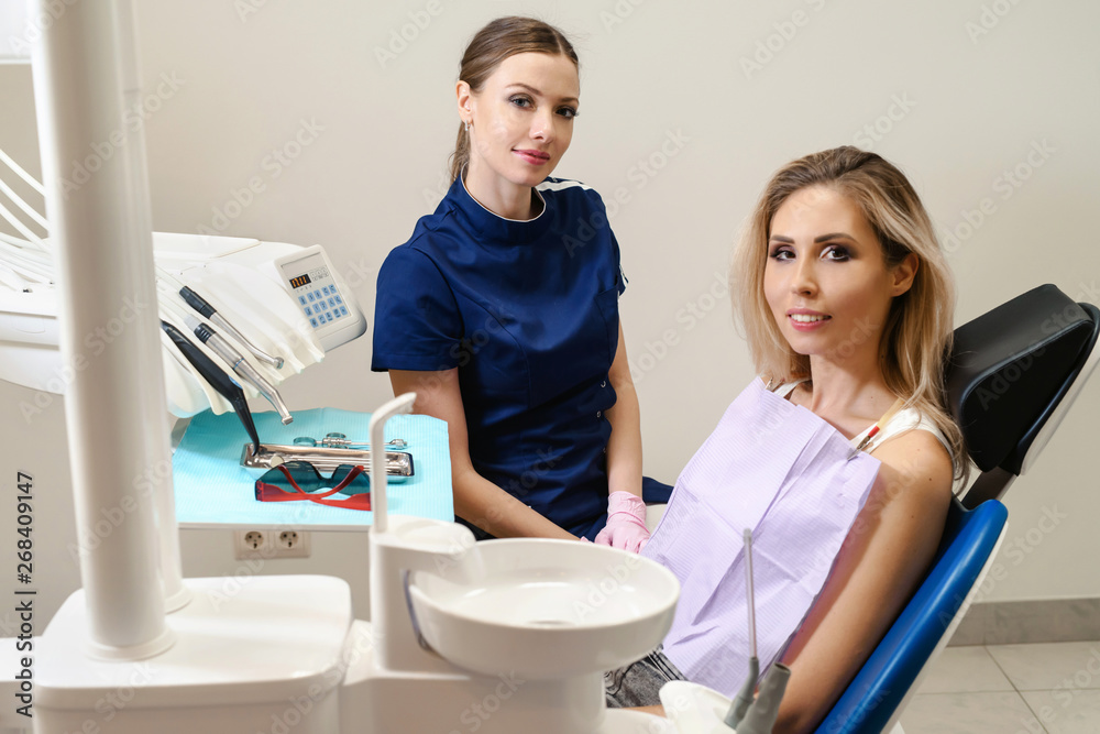 The woman came to see the dentist. Young woman having dental check-up in dentist's office, smiling, looking at camera. Happy patient and dentist concept. The woman came to see the dentist. Young woman having dental check-up in dentist's office, smiling, looking at camera. Happy patient and dentist concept.