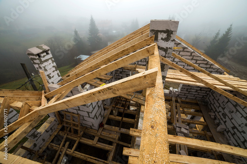 Top view of roof frame from wooden lumber beams and planks on walls made of hollow foam insulation blocks. Building, roofing, construction and renovation concept.