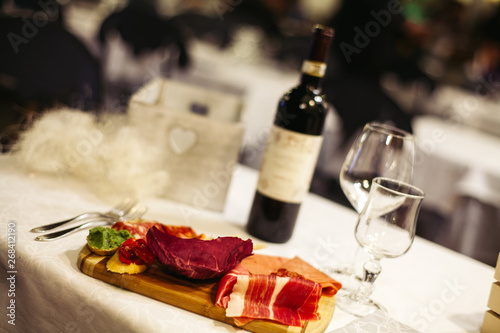 Fototapeta Naklejka Na Ścianę i Meble -  Table setting: white plates, rustic cloth with salami, cheese, vine, ham and wine bottle