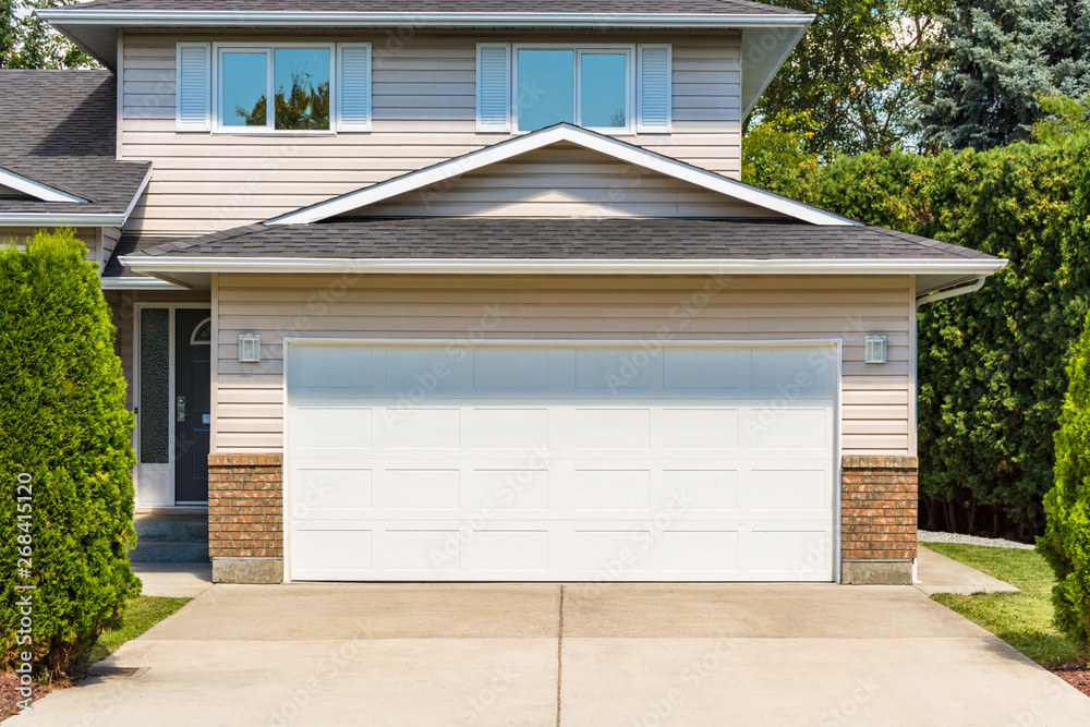 Wide garage door of residential house with concrete driveway in front - obrazy, fototapety, plakaty 