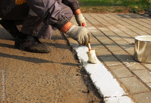 paints the border with white paint. city services, close-up