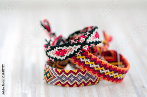 Three handmade homemade colorful natural woven bracelets of friendship isolated on light wooden background