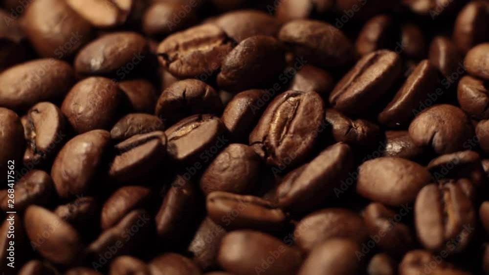 Macro shot of coffee beans rotating along its axis. Beans factory mixing, close up. Roasted coffee bean. Beans of Coffee Raining at Slow Motion. Morning black coffee texture. Macro shot of coffee beans rotating along its axis. Beans factory mixing, close up. Roasted coffee bean. Beans of Coffee Raining at Slow Motion. Morning black coffee texture.