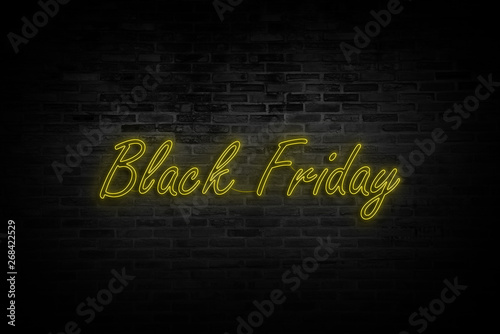 Black Friday sale. Modern neon yellow billboard on brick wall.