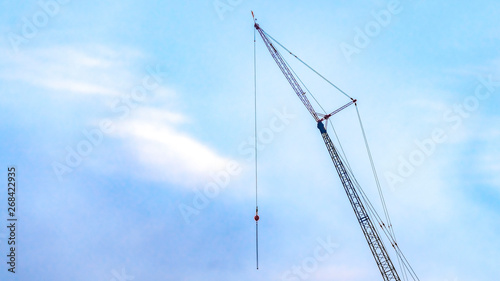 Panorama A lifting crane viewed against a beautiful blue sky filled with cottony clouds