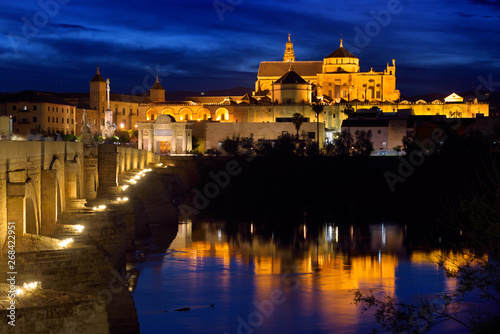 Cordoba Cathedral Mosque reflected in Guadalquivir River with Roman Bridge at twilight