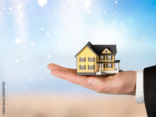 Building, mortgage, real estate and property concept - close up of hand holding house model