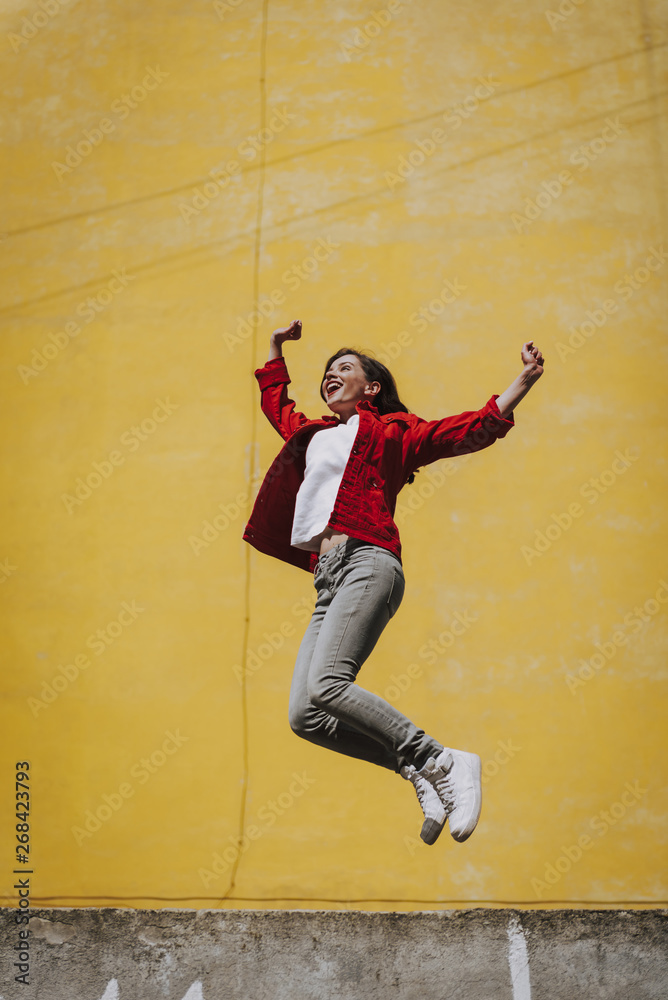 Pretty cheerful hipster girl jumping up on parapet