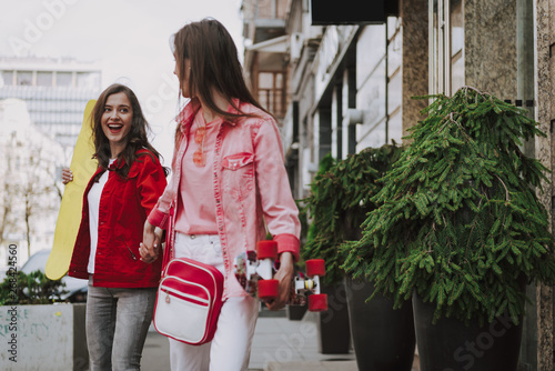 Two happy hipster girls walking with skateboards photo