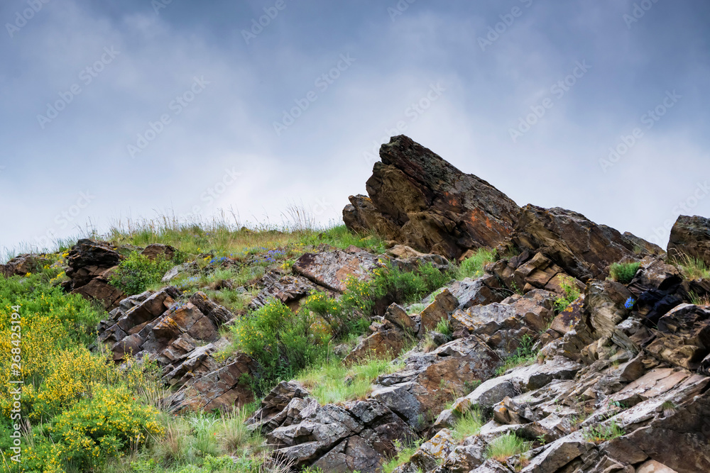 Stone cavern in green steppe landscape view with cloudy sky