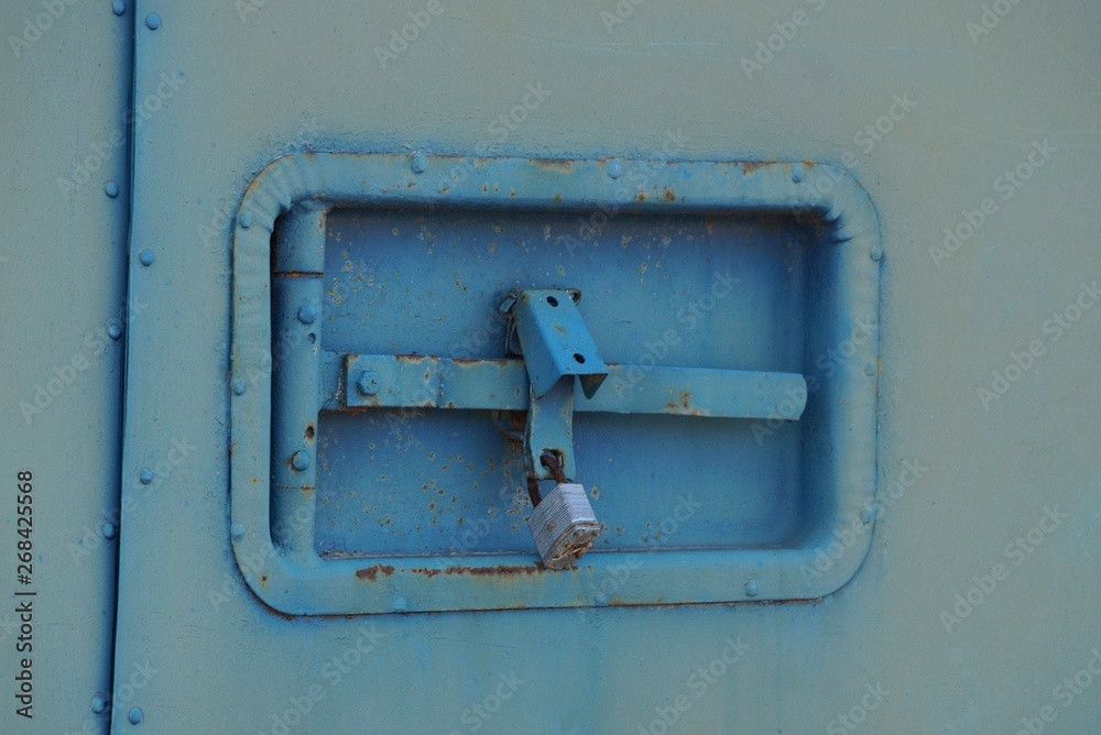 padlock and latch on the old blue gray iron wall