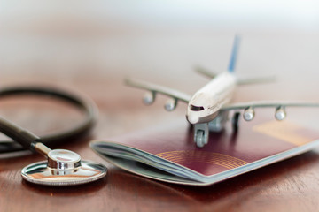 Airplane on top of a passport document and a Stethoscope. Healthcare and travel insurance concept
