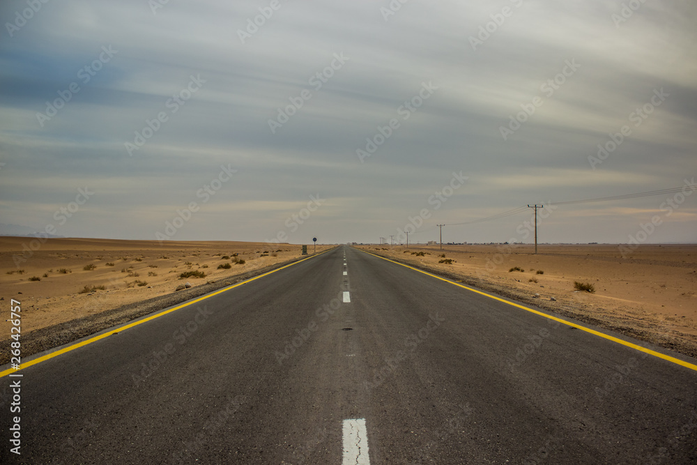 Fototapeta premium car highway road desert sand dunes calming scenic landscape in cloudy weather time, daily planet concept picture from Middle East Earth region in Jordan country 