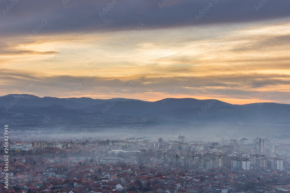 Stunning, soft view of golden sunset sky above scenic cityscape covered by haze and mist