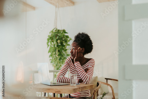 Half length of calm African woman sitting at table in cafe