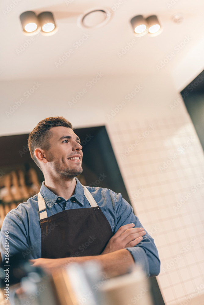 Fototapeta premium Cheerful barista looking into the distance and smiling