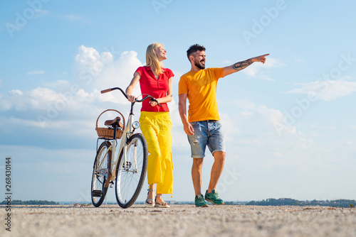 Happy young couple riding bicycles. Retirement. Young riders enjoying themselves on trip. During summer holidays vacation. Beautiful summer day.