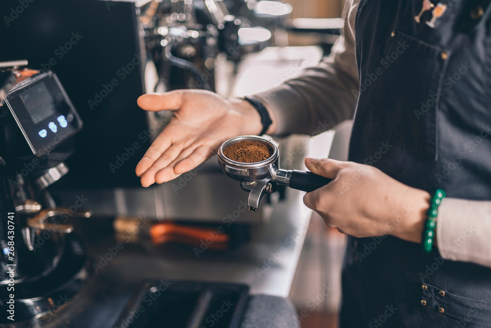 Hand of barista tapping filter holder with coffee
