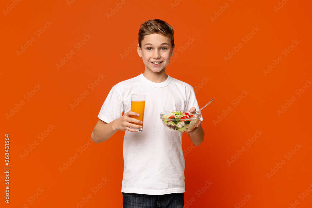 Smiling little boy eating vegetable salad and orange juice Smiling little boy eating vegetable salad and orange juice