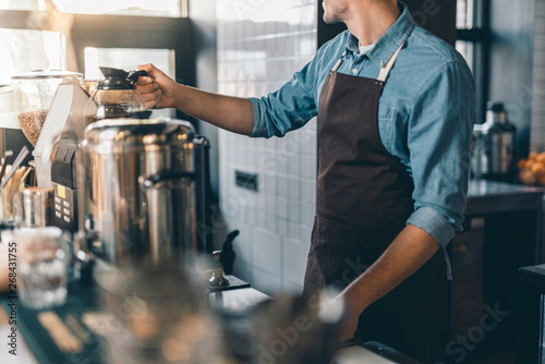 Barista placing coffee jug on the top of coffee machine